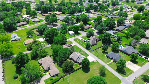 Residential neighborhood along Jefferson and Gentry Ave in Checotah, McIntosh County, Oklahoma, row of single-family houses with large backyard, grassy lawn, lush green tall mature trees, aerial photo