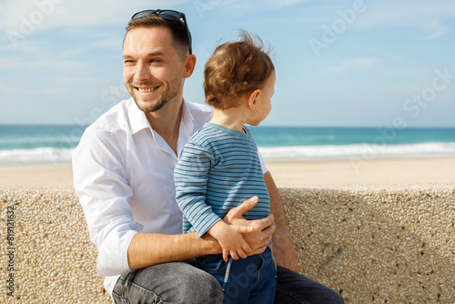 Young happy father with his little son on the embankment against the backdrop of the sea. photo