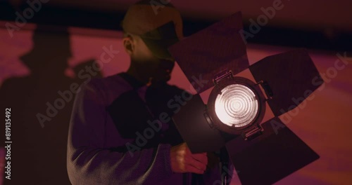 Technician setting up lights on film set