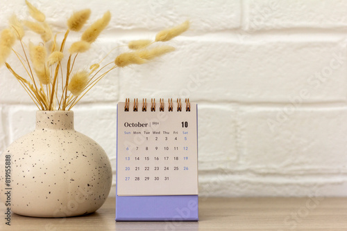 Desktop calendar for August 2024. Monthly planning calendar and vase with dried flowers on the table.