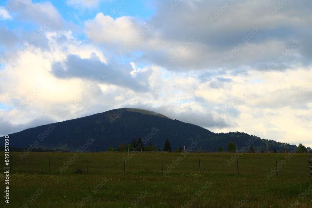 A field with a fence and mountains in the background A field with a fence and mountains in the background