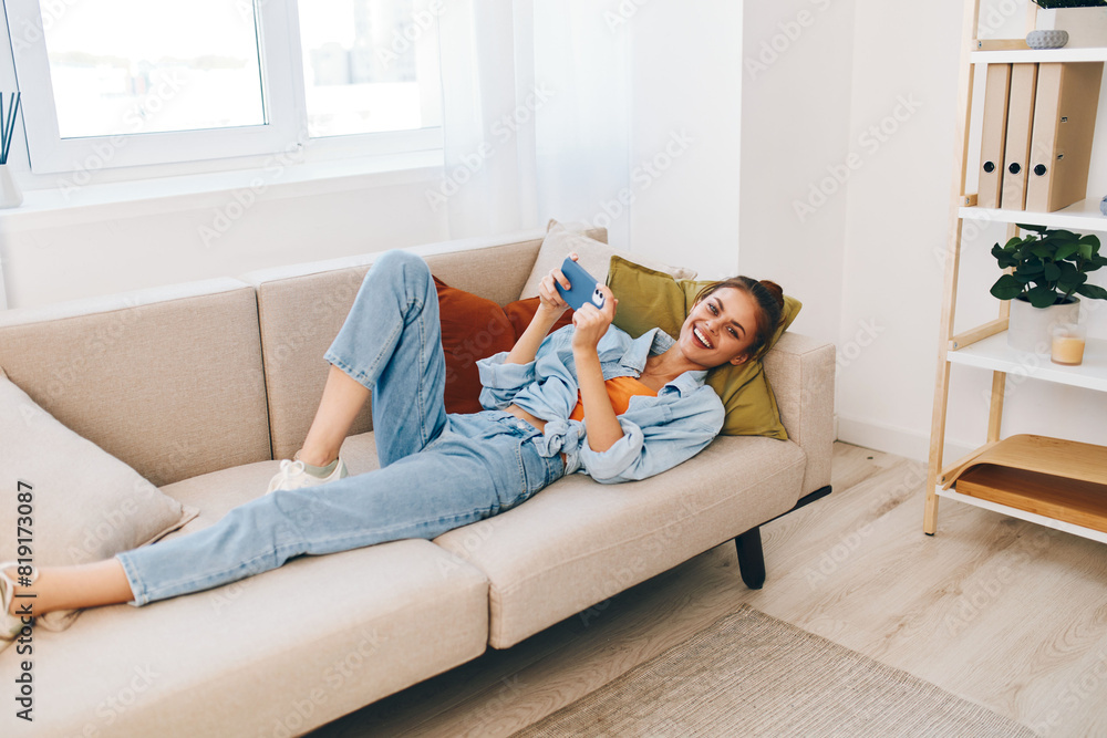 Happy Woman Relaxing on Sofa, Holding Mobile Phone and Smiling at Selfie Happy Woman Relaxing on Sofa, Holding Mobile Phone and Smiling at Selfie