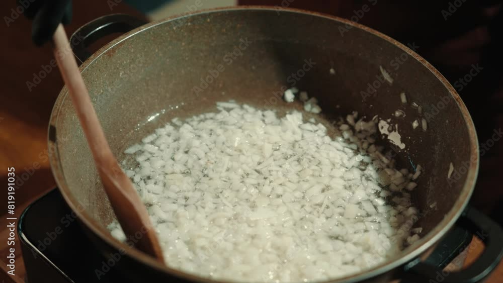 Chopped onions are fried in a pan in vegetable oil, stirring occasionally. Close-up. Chopped onions are fried in a pan in vegetable oil, stirring occasionally. Close-up.