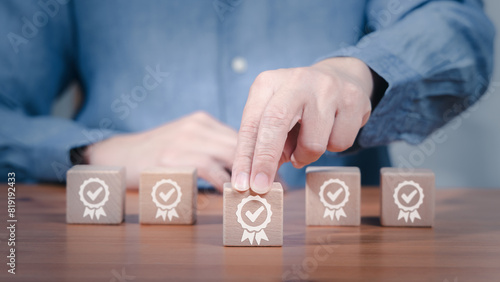A person is placing a wooden block with a certificate checkmark icon on it in concept of certified professional in quality of service, control and development.