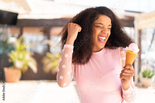 Young African American woman with a cornet ice cream at outdoors celebrating a victory