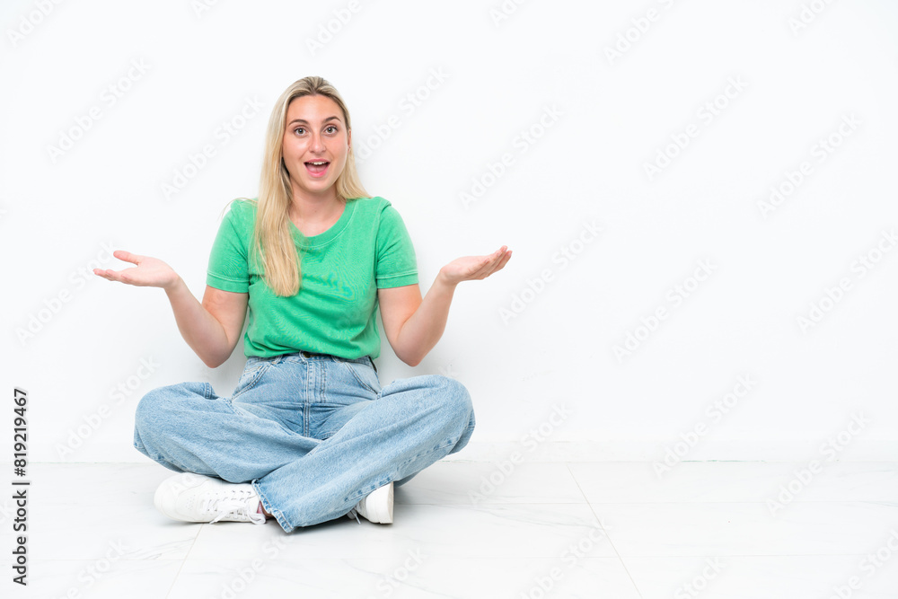 Young caucasian woman sitting on the floor isolated on white background with shocked facial expression Young caucasian woman sitting on the floor isolated on white background with shocked facial expression