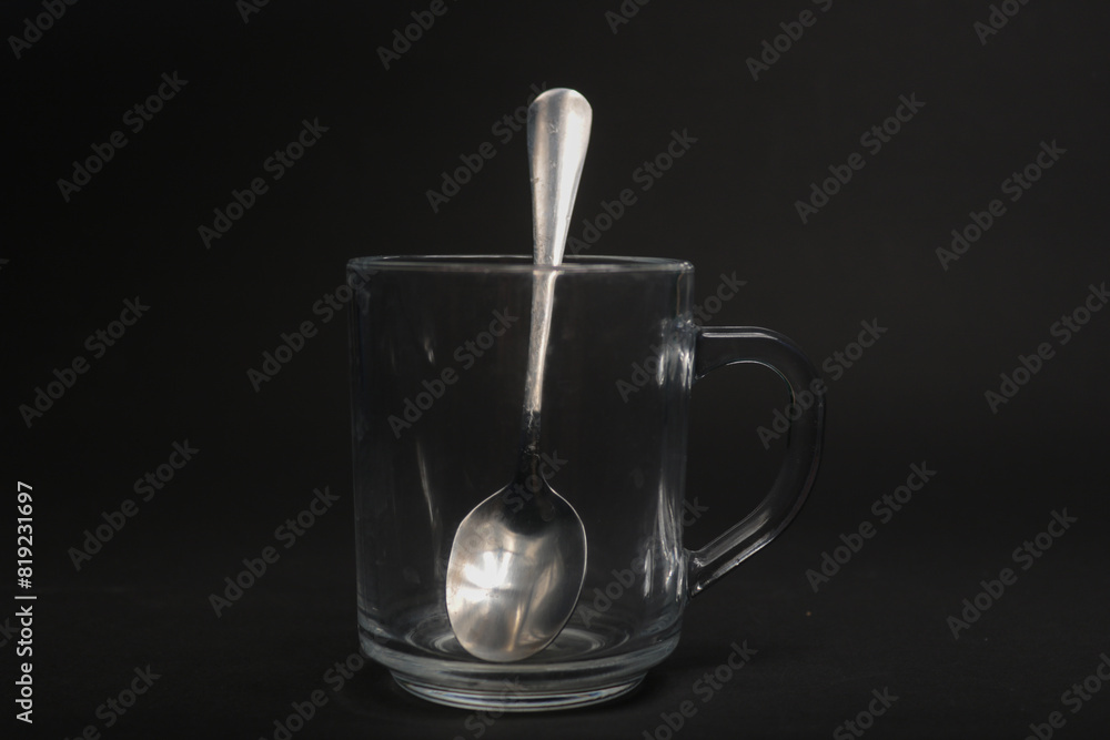 transparent mug with a teaspoon on a black background transparent mug with a teaspoon on a black background