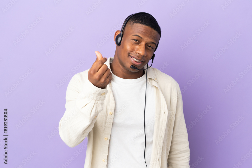 Telemarketer latin man working with a headset isolated on purple background making money gesture Telemarketer latin man working with a headset isolated on purple background making money gesture