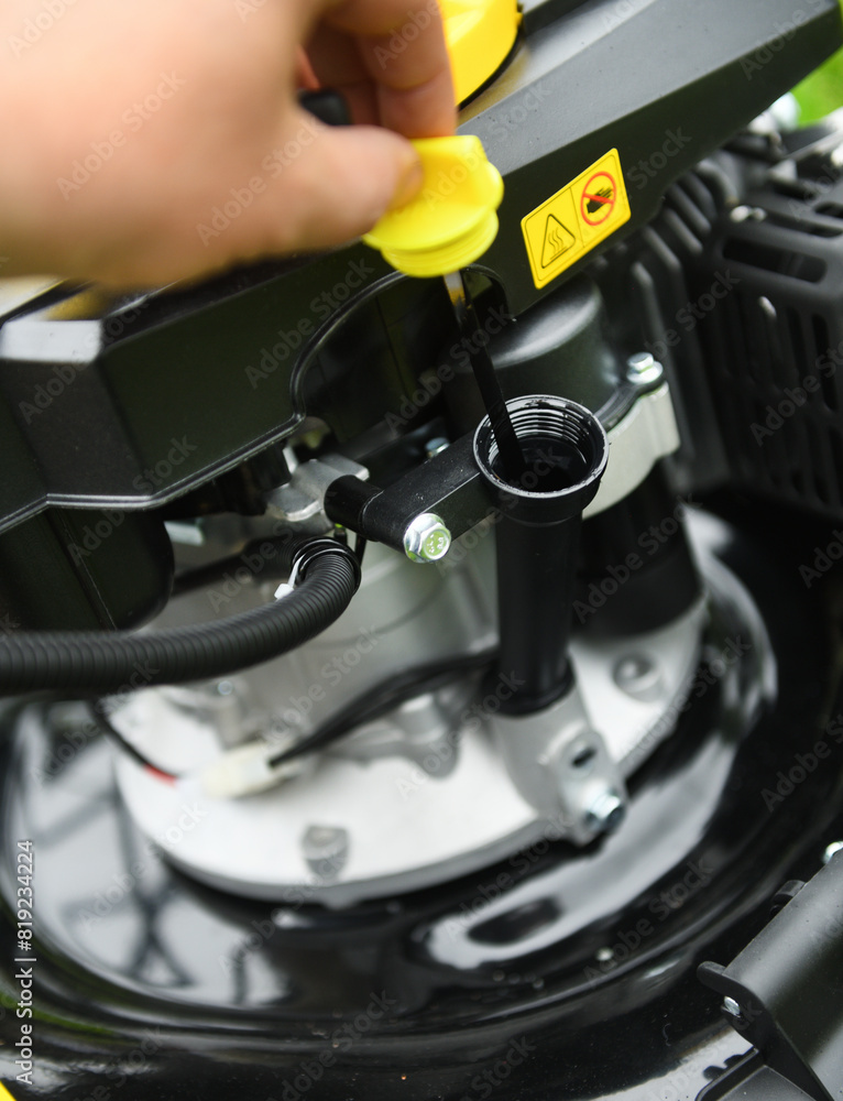 A worker checks the oil level in a new lawn mower. Checking the oil in