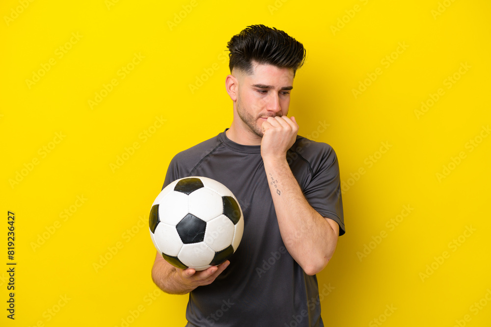 Handsome young football player man isolated on yellow background having doubts Handsome young football player man isolated on yellow background having doubts