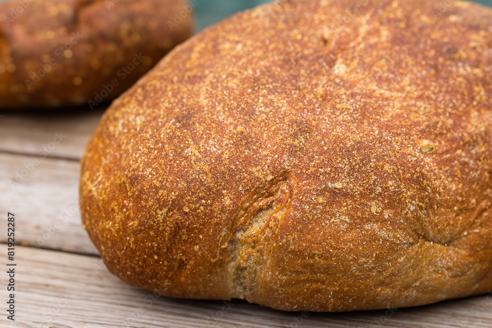 Bread. Close up of rustic bread loaf on wooden table. Baker or chef holding fresh made bread. Sourdough bread with crispy crust on wooden shelf. Bakery goods. Loaves of different bread and wheat ears.