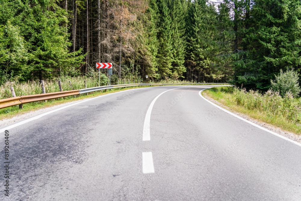 Fototapeta premium Empty asphalt street road in the mountains through the pine forest in Romania.