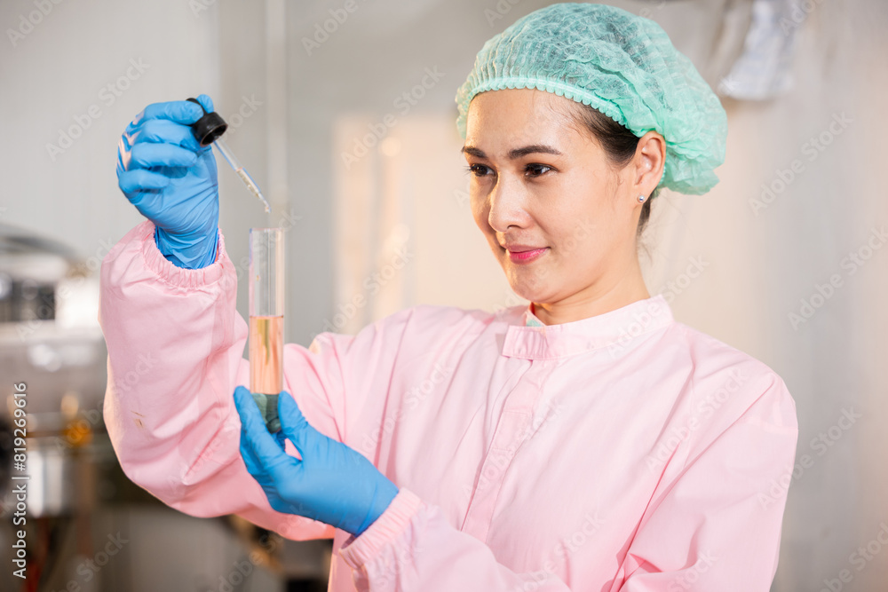 At juice beverage factory woman food engineer executes food and beverage quality and safety testing using test tubes to sample basil or chia seeds in bottled products in laboratory control. At juice beverage factory woman food engineer executes food and beverage quality and safety testing using test tubes to sample basil or chia seeds in bottled products in laboratory control.