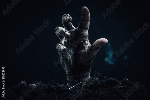 Zombie hand coming out of the ground on a dark background. Horror theme. photo