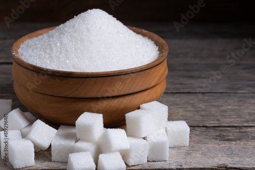 Fotografie Granulated sugar in a wooden cup, a scattering of refined sugar cubes