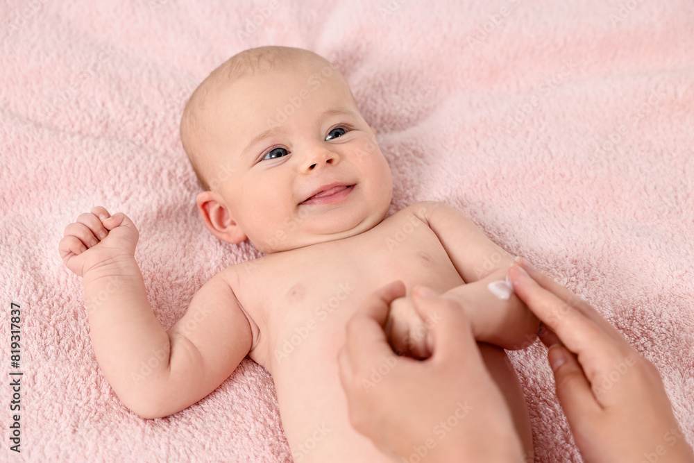 Woman applying body cream onto baby`s skin on bed, top view Woman applying body cream onto baby`s skin on bed, top view