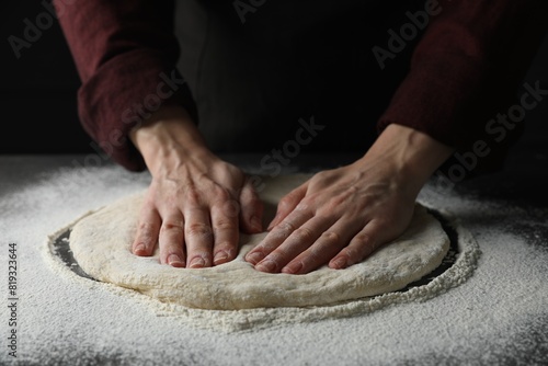 Woman kneading pizza dough at table, closeup