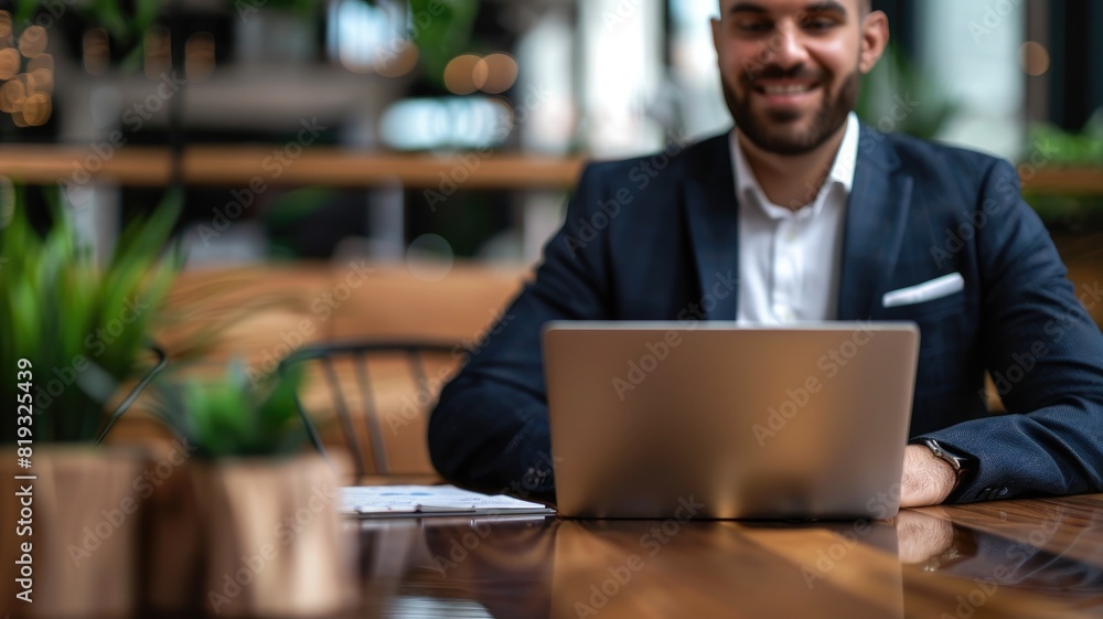 Smiling man working on laptop in cozy, plant-filled cafe Smiling man working on laptop in cozy, plant-filled cafe