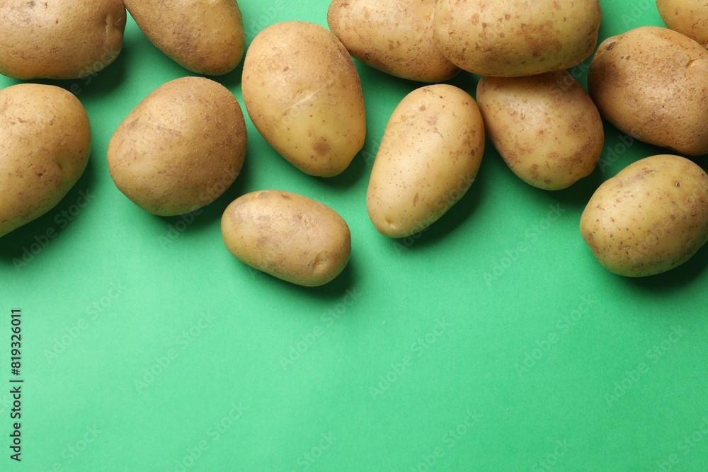 Fresh raw potatoes on green background, flat lay. Space for text Fresh raw potatoes on green background, flat lay. Space for text