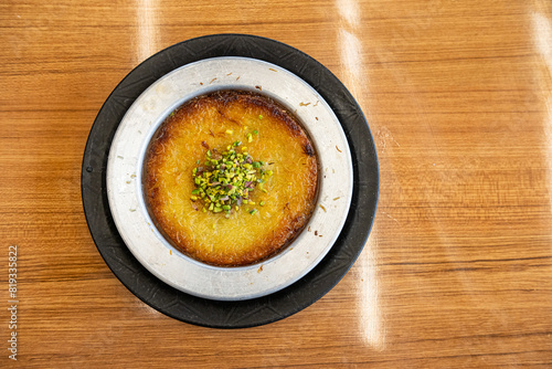 Delicious traditional Turkish kunefe with pistachio on it. Served hot and with syrup. Turkish Künefe, Hot and Cheesy Southeastern Dessert. photo