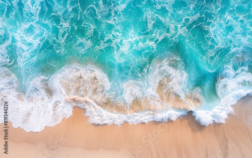 Aerial view of turquoise ocean waves meeting sandy shore.