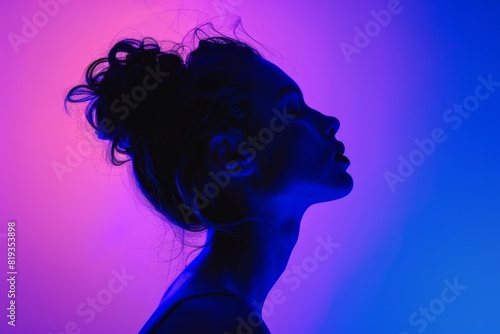 An impactful image showcasing a side profile of a woman with her hair up, backlit by blue and pink hues, providing a sense of contemplation