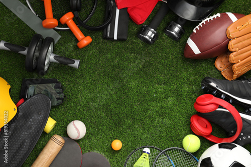 Frame of different sports equipment on green grass, flat lay. Space for text