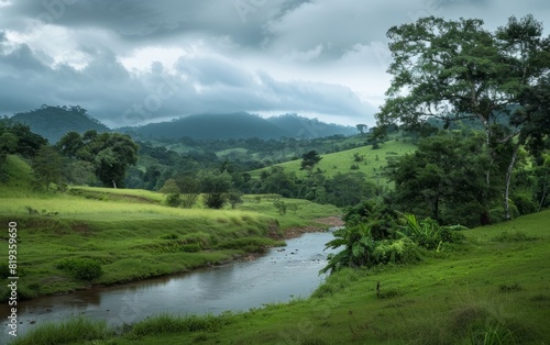 Serene riverside with lush trees and rolling hills under a cloudy sky.