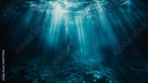 A dark blue ocean floor with light rays shining down, creating an underwater scene. The background is a deep sea, creating a sense of depth and mystery. photo