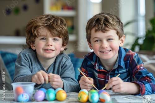 Two happy boys painting Easter eggs together
