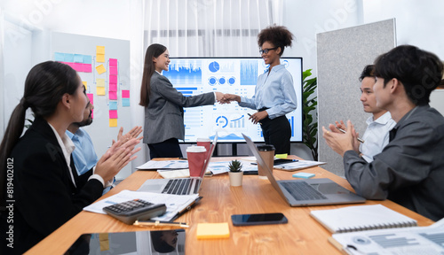 Diverse coworker celebrate with handshake and teamwork in corporate workplace. Happy business people united by handshaking after successful meeting or business presentation on data analysis. Concord