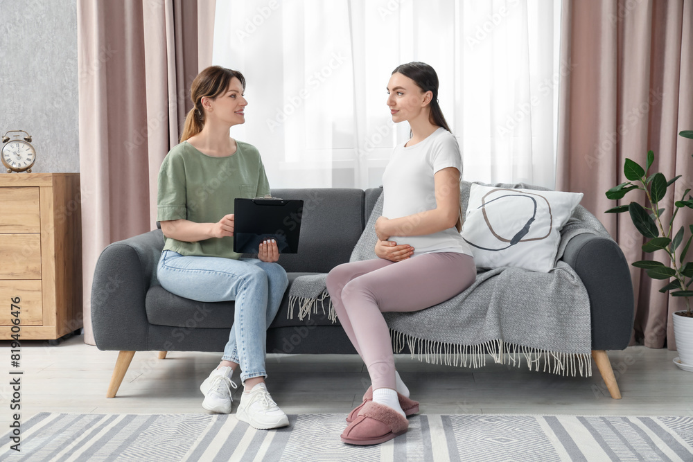 Doula working with pregnant woman on sofa at home. Preparation for child birth Doula working with pregnant woman on sofa at home. Preparation for child birth