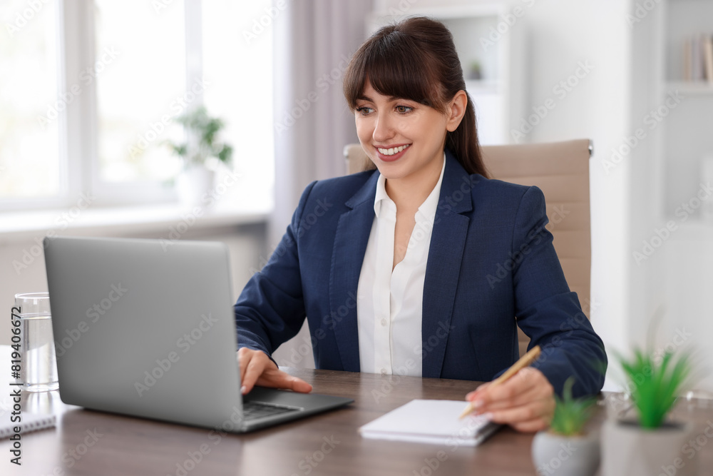 Woman taking notes during webinar at wooden table indoors Woman taking notes during webinar at wooden table indoors