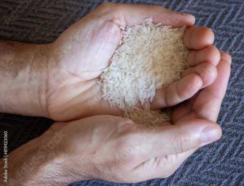Very close-up photo of rice grains on young man hands. Dark background