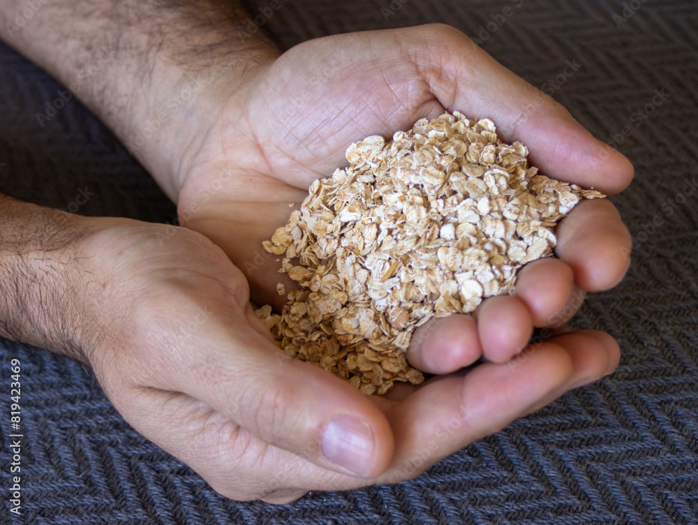 Above photo of handful of oats in the hands of a young man. Dark background Above photo of handful of oats in the hands of a young man. Dark background