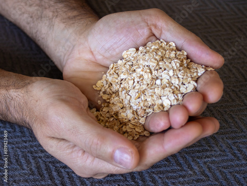 Above photo of handful of oats in the hands of a young man. Dark background © Vero Dibe