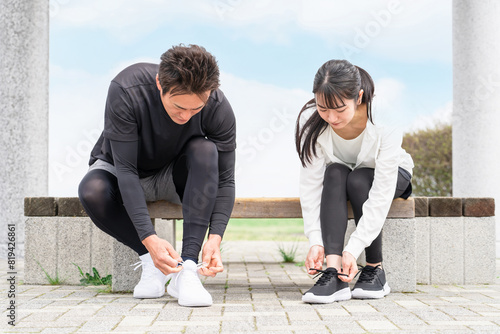 靴紐を結んで運動の準備をするアジア人の男女 