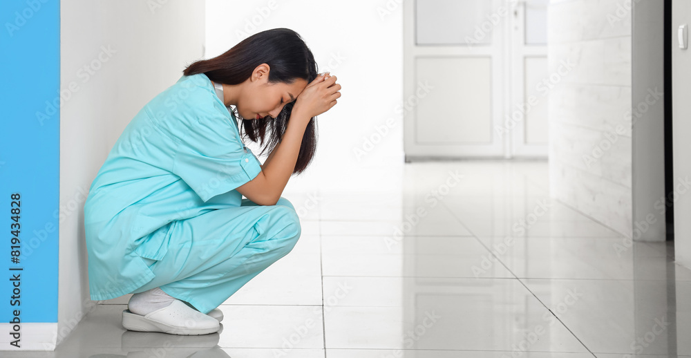 Stressed female Asian medical intern in clinic Stressed female Asian medical intern in clinic