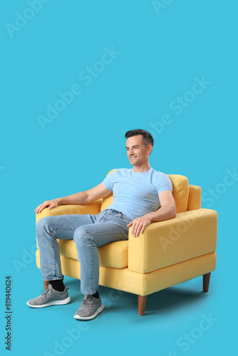 Handsome man sitting in yel...