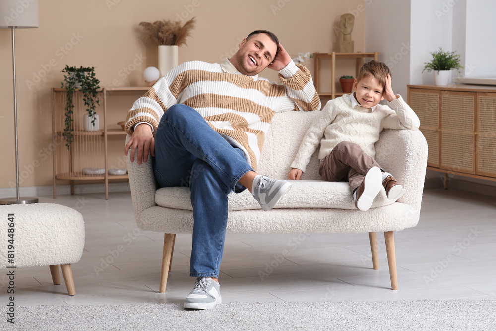 Happy father and his little son sitting on sofa at home Happy father and his little son sitting on sofa at home