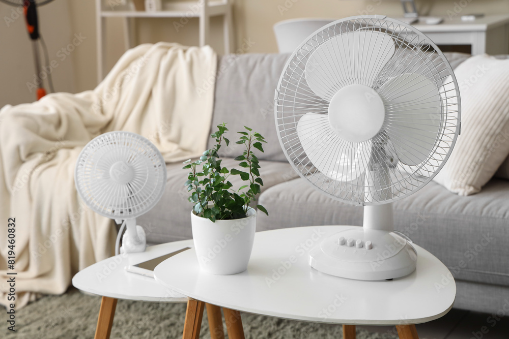Modern electric fans with houseplant and tablet on coffee table at home Modern electric fans with houseplant and tablet on coffee table at home