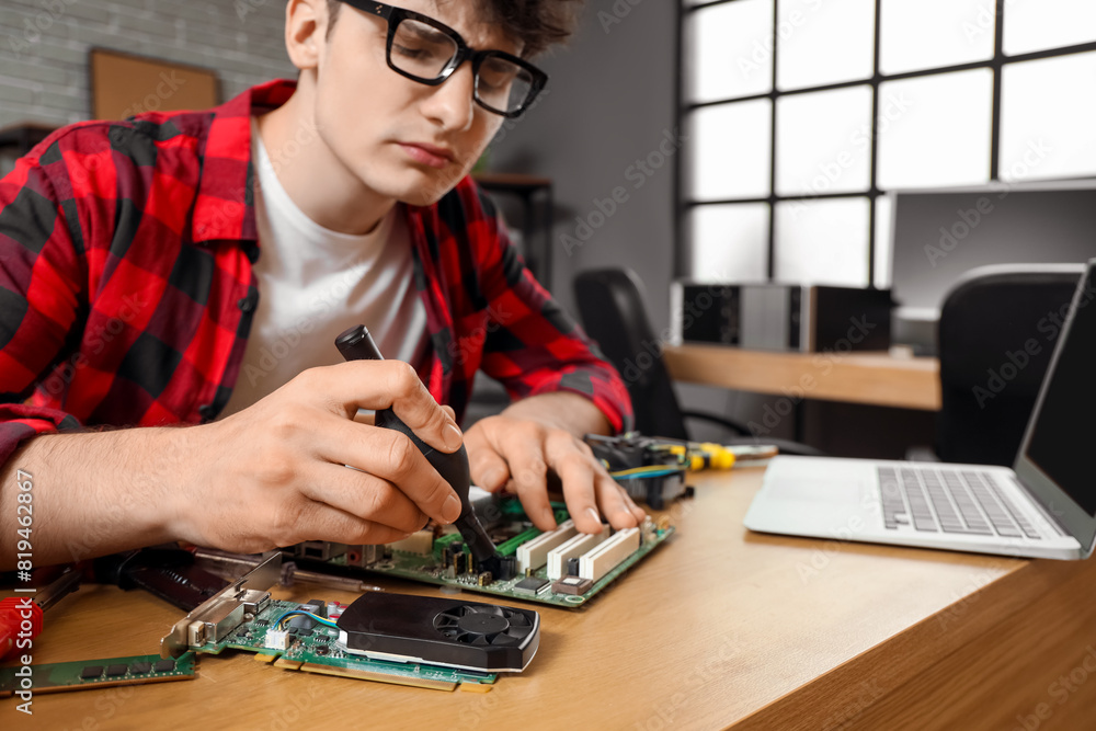 Fototapeta premium Male technician repairing computer board at table in service center, closeup