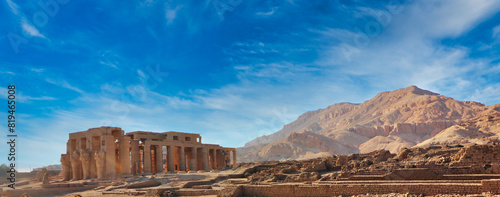 Wide angle view of the Ramesseum, the Mortuary Temple of Pharoah Ramesses II the Great with the backdrop of the Theban Hills on a bright afternoon with blue skies at Luxor, Egypt 