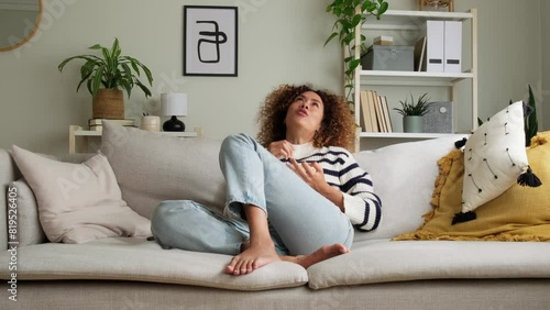 Young multiracial woman watching movie at home eating popcorn, sitting on the couch. 4k resolution video. 