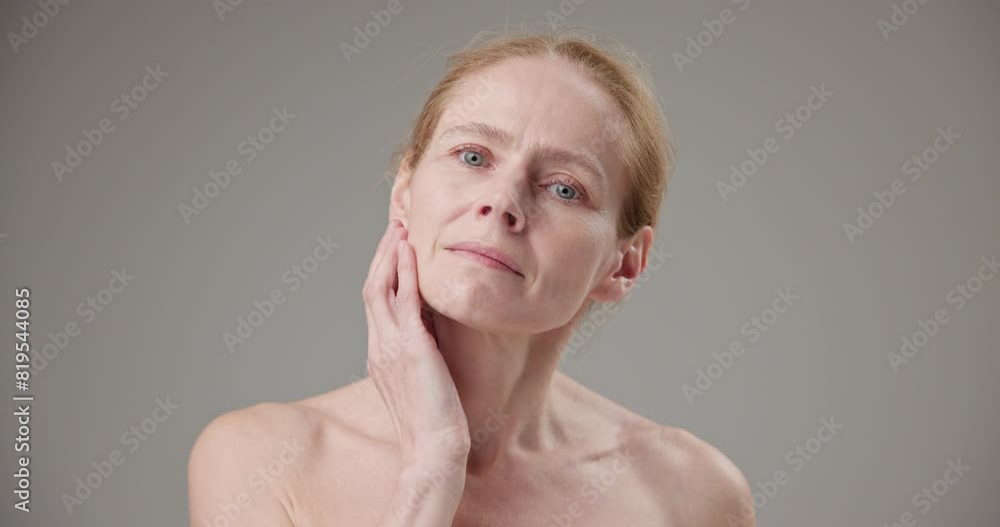 Anti age, Beauty, health and dry skin care concept - beautiful middle-aged mature Caucasian woman in her 50s touching her face skin and looking at the camera with a slight smile Anti age, Beauty, health and dry skin care concept - beautiful middle-aged mature Caucasian woman in her 50s touching her face skin and looking at the camera with a slight smile
