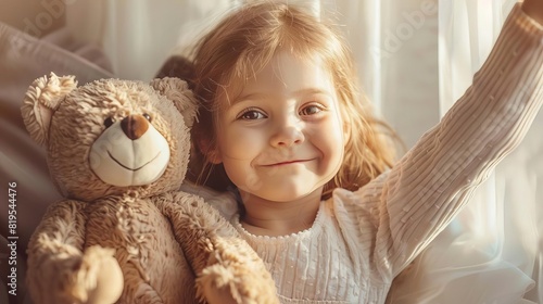 Happy little girl with teddy bear in cozy room, smiling and waving in warm natural light, creating a heartwarming moment of childhood joy. photo