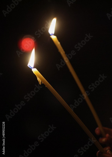 Details with burning candles in the hands of a person during a religious ceremony