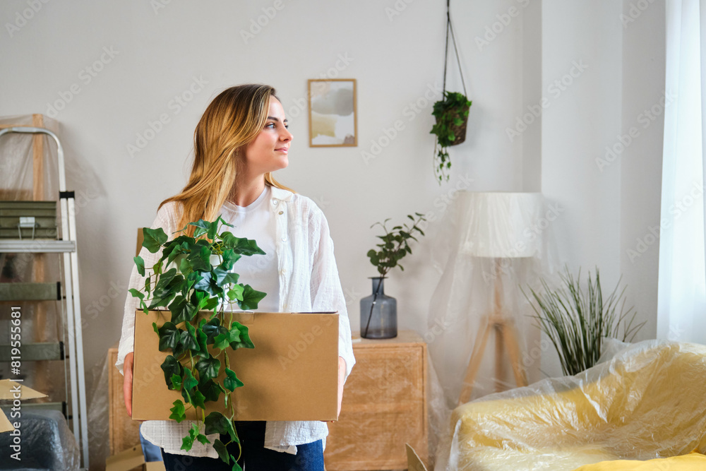 Caucasian woman holding a moving cardboard box to settle in her new home. Student residence relocation. Caucasian woman holding a moving cardboard box to settle in her new home. Student residence relocation.