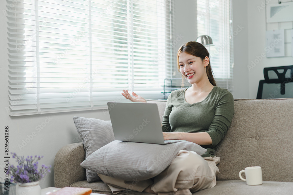 Happy asian woman waving during a video call on laptop at home. Work life balance concept Happy asian woman waving during a video call on laptop at home. Work life balance concept