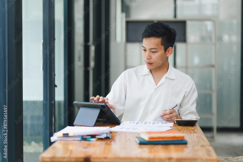 Young man working on tablet in bright office. Young man working on tablet in bright office.